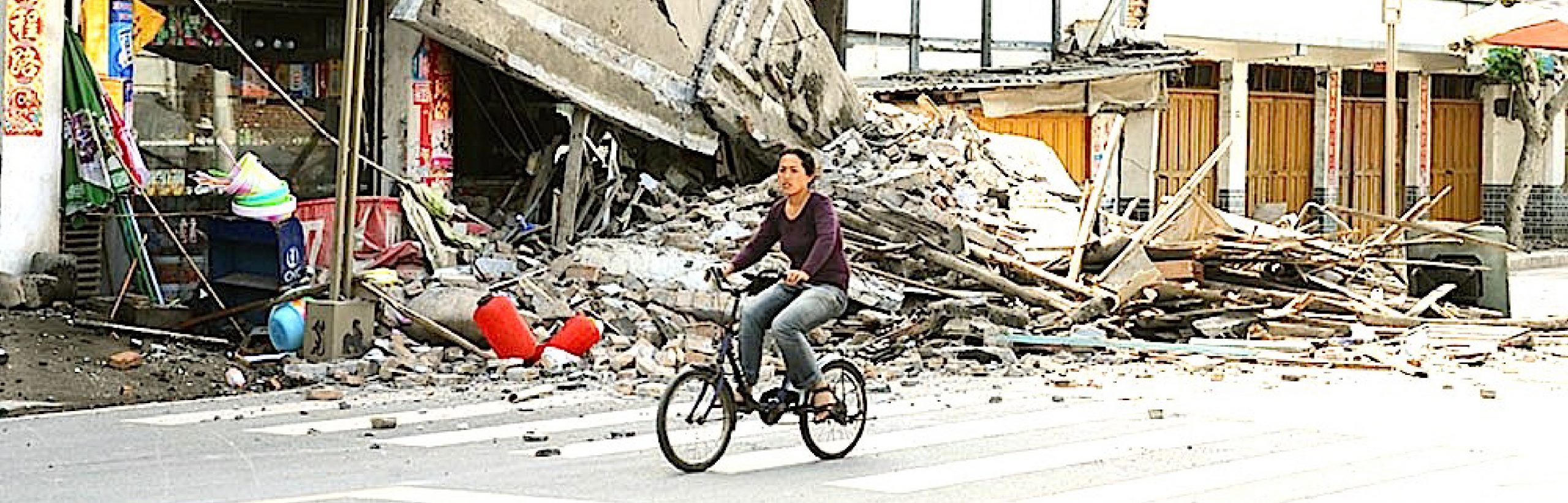 Woman riding a bike through the debris of a collapsed building